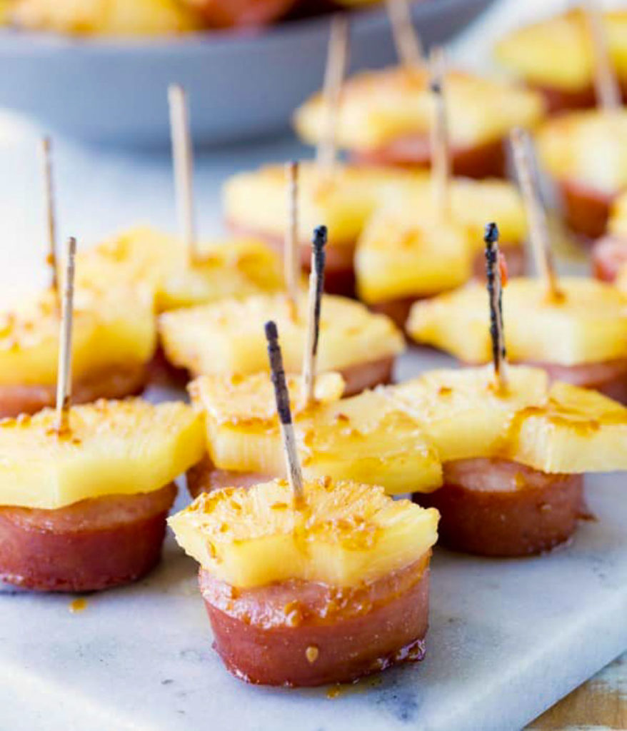 several kielbasa slices with slice of pineapple skewered with a toothpick