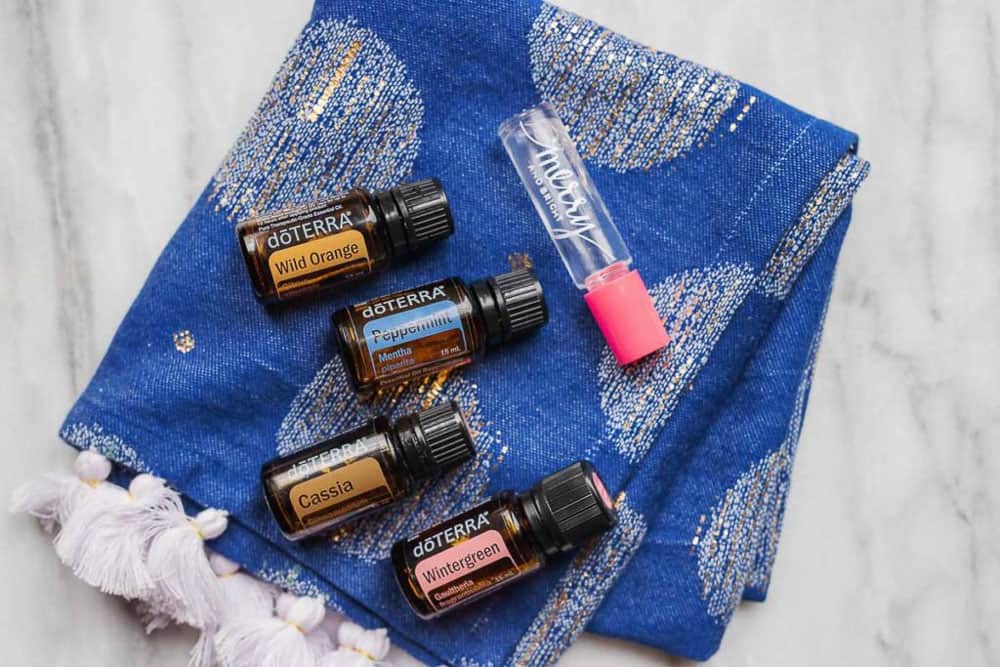 A blue decorated cloth folded up with four doTerra bottles and one Merry and Bright roll-on perfume on top of it.