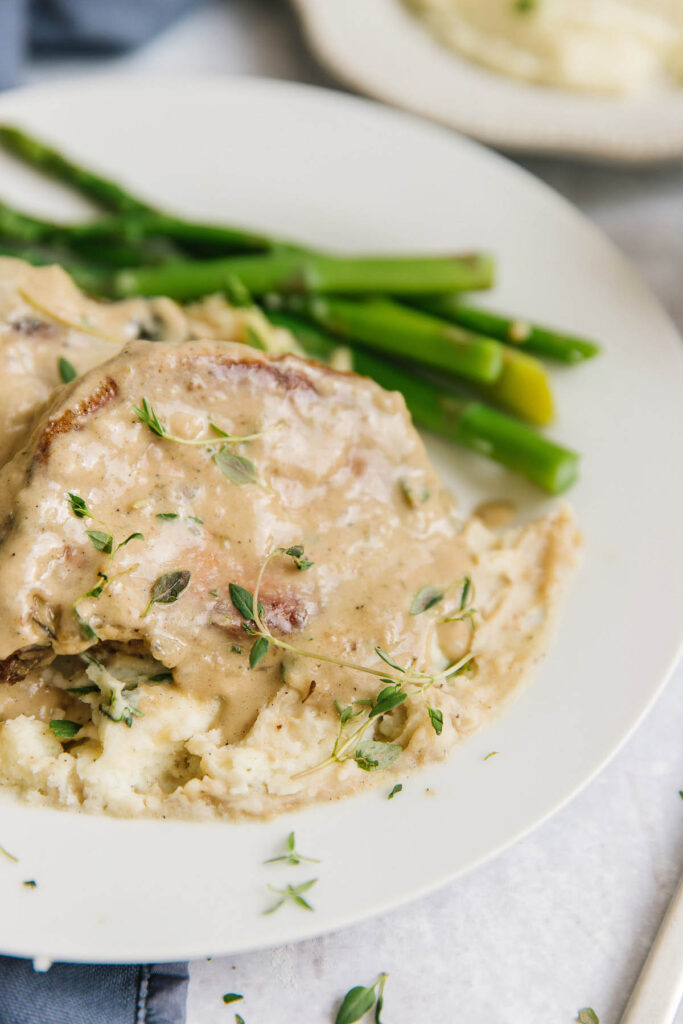 Closeup of Gravy covered pork chops with asparagus on the side. 