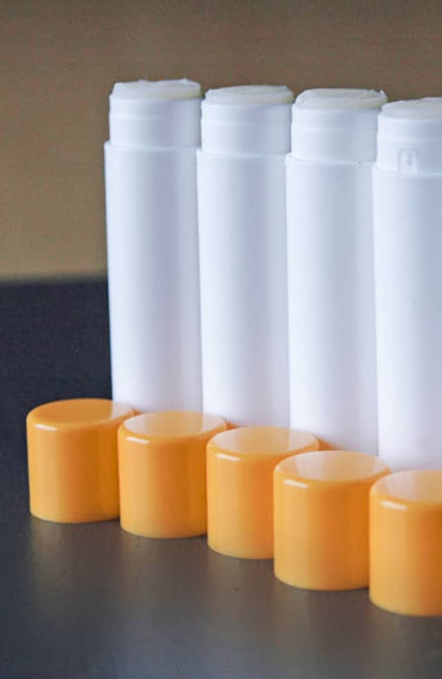 White tubes with orange lids of homemade chapstick recipe. 