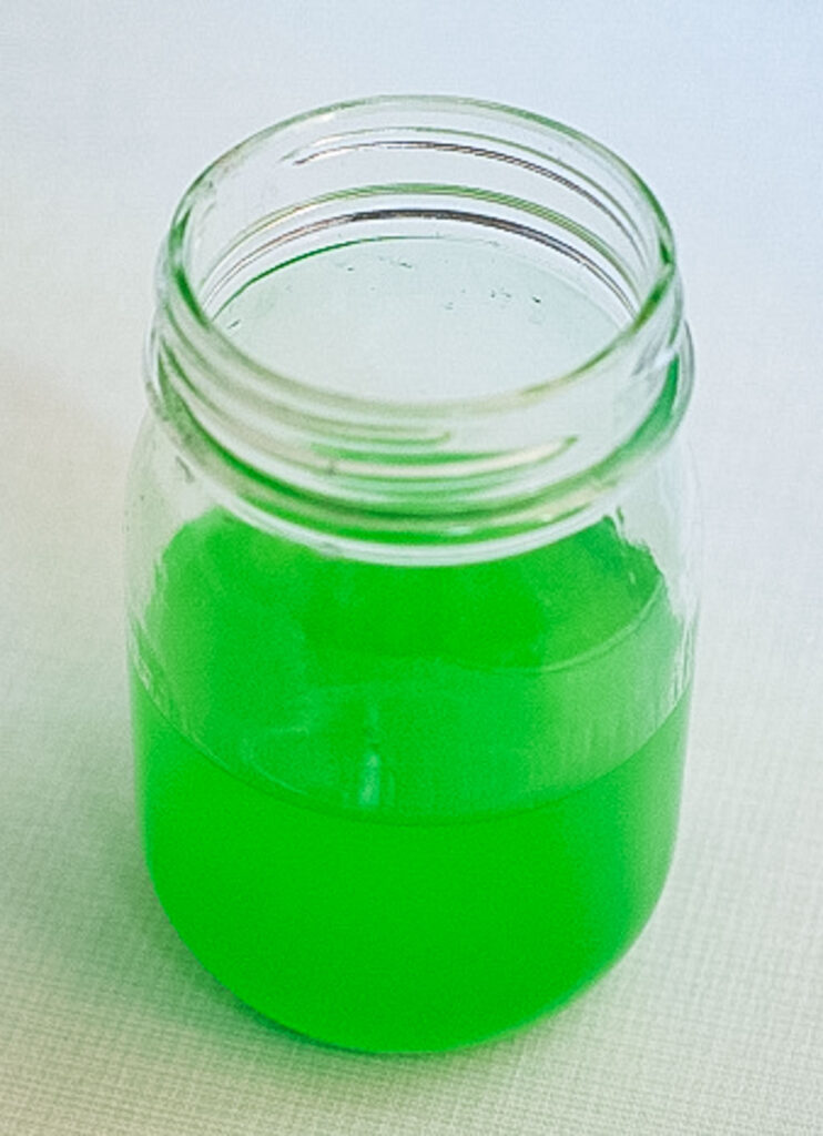 Green Homemade hand sanitizer in a small glass mason jar. 