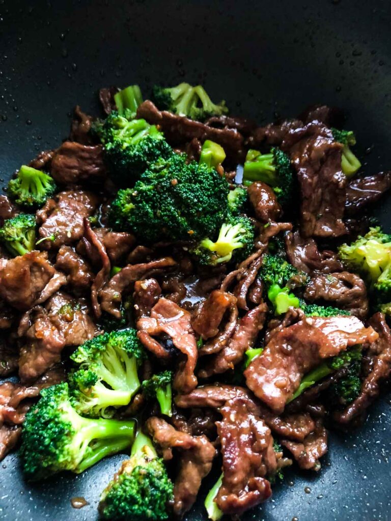 Strips of beef and broccoli cooked altogether smothered in teriyaki sauce in a nonstick pan.