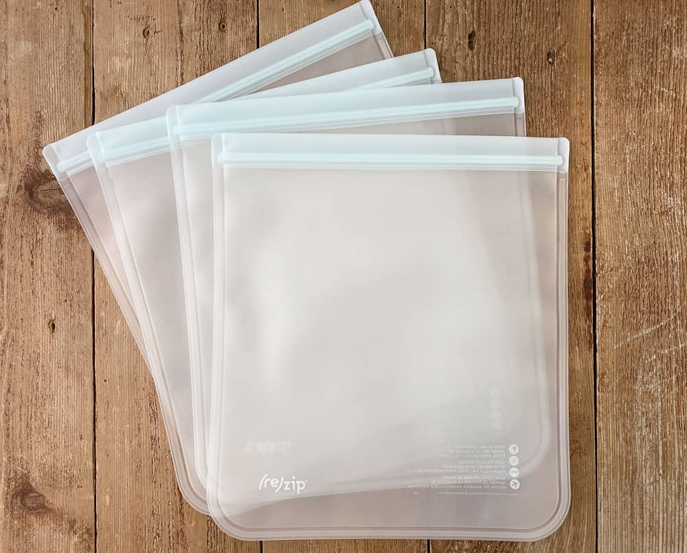 4 empty Rezip Gallon Sized Reusable Freezer Bags on a wood surface