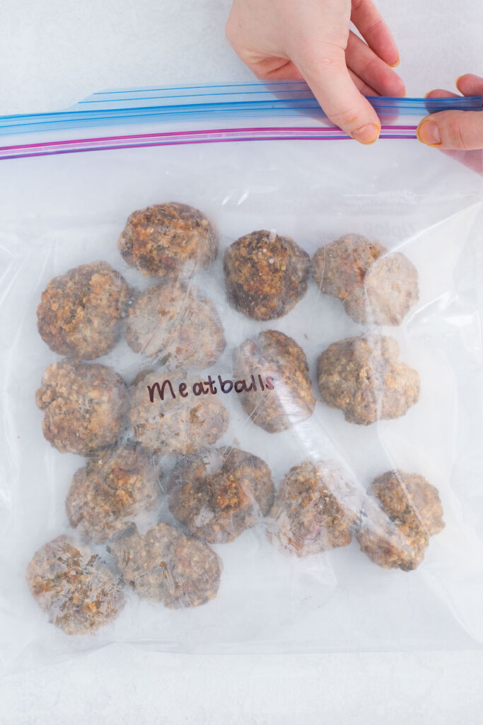 A zippered bag with 16 individual meatballs in it with the word meatballs written in black marker.