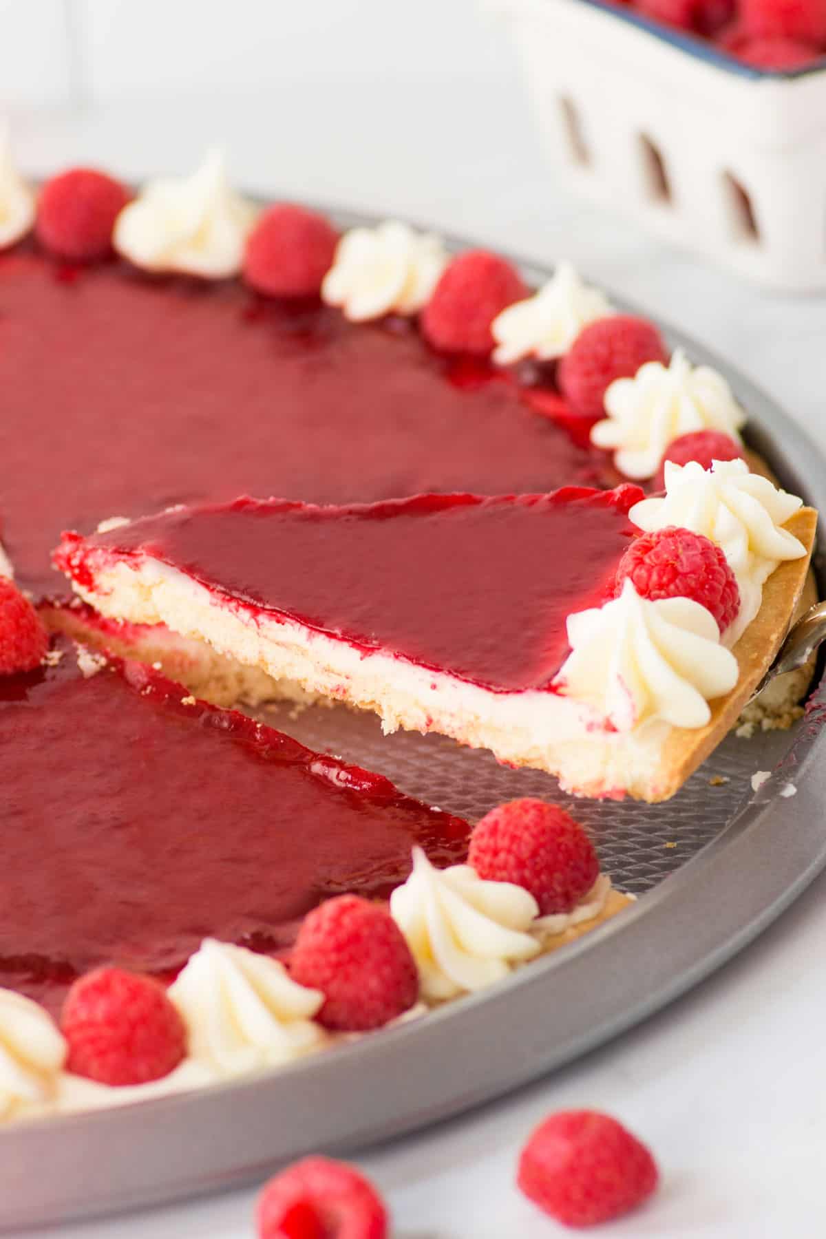 17 Frugal and Free Mother's Day Gift Ideas - Raspberry Tart with a cut piece with a metal spatula with a metal pan.