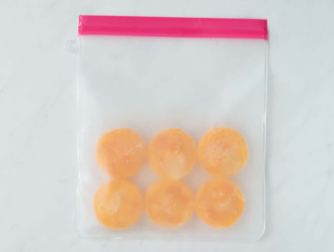Freezing eggs - Six frozen eggs in a resealable bag sitting on a white counter.