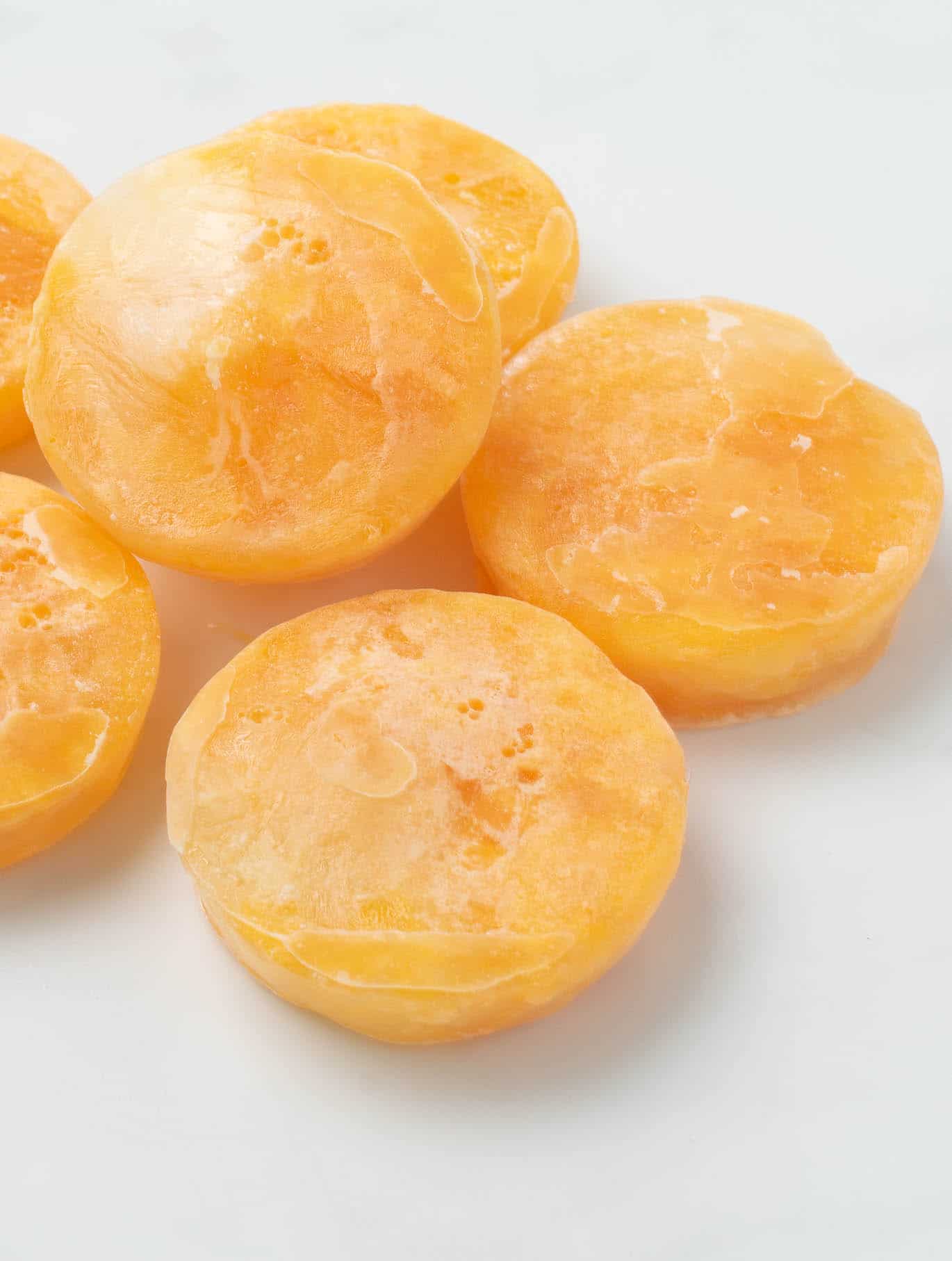 A closeup of frozen egg yolks piled on each other on a white counter.