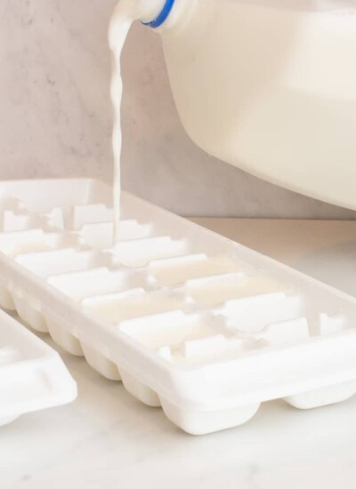 Milk pouring into a white ice cube tray.