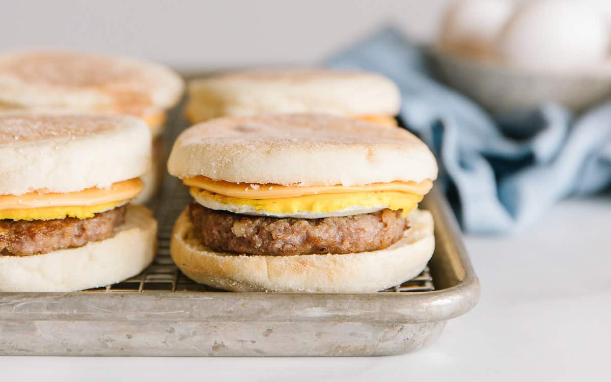 A cookie sheet holds four sausage mcmuffin breakfast sandwiches.