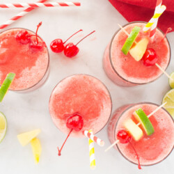Glasses of pink frozen party stush with fruit toppings.
