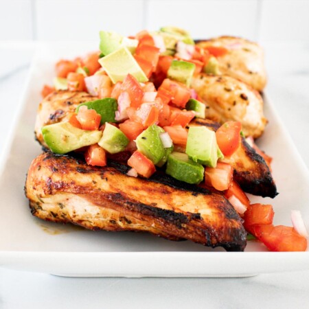Serving plate of lime cilantro chicken with avocado salsa.