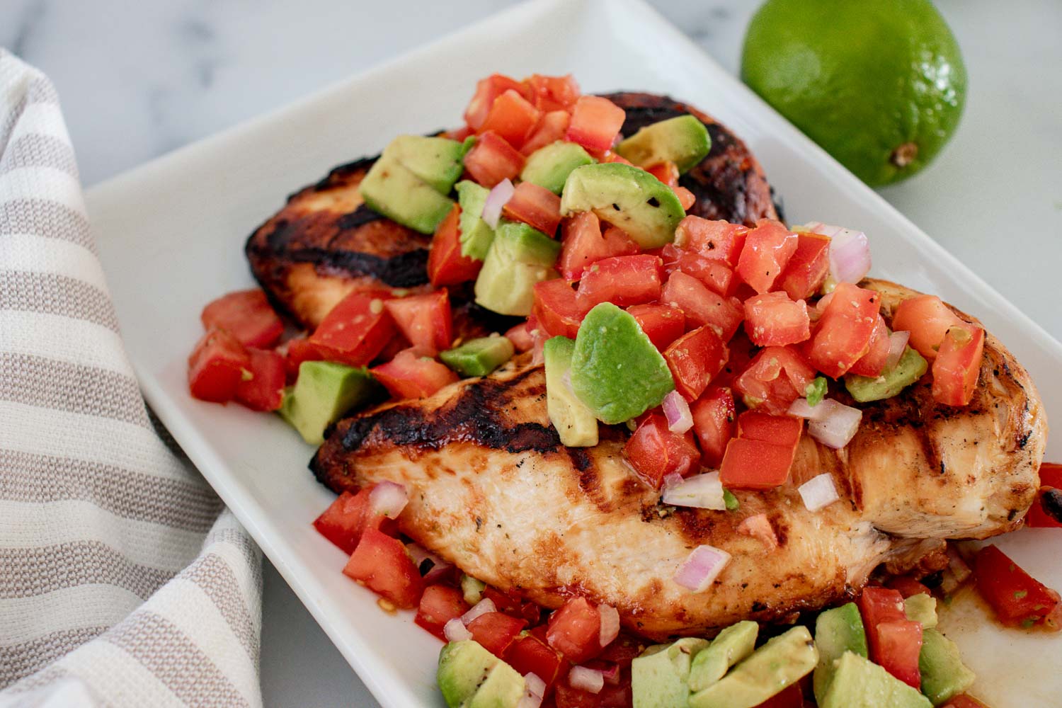 Cilantro lime chicken grilled and covered in a fresh avocado salsa with tomatoes and onions. 
