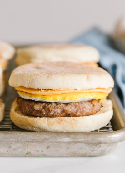 sausage mcmuffin copycat recipe - 4 sandwiches on a baking pan with eggs in background