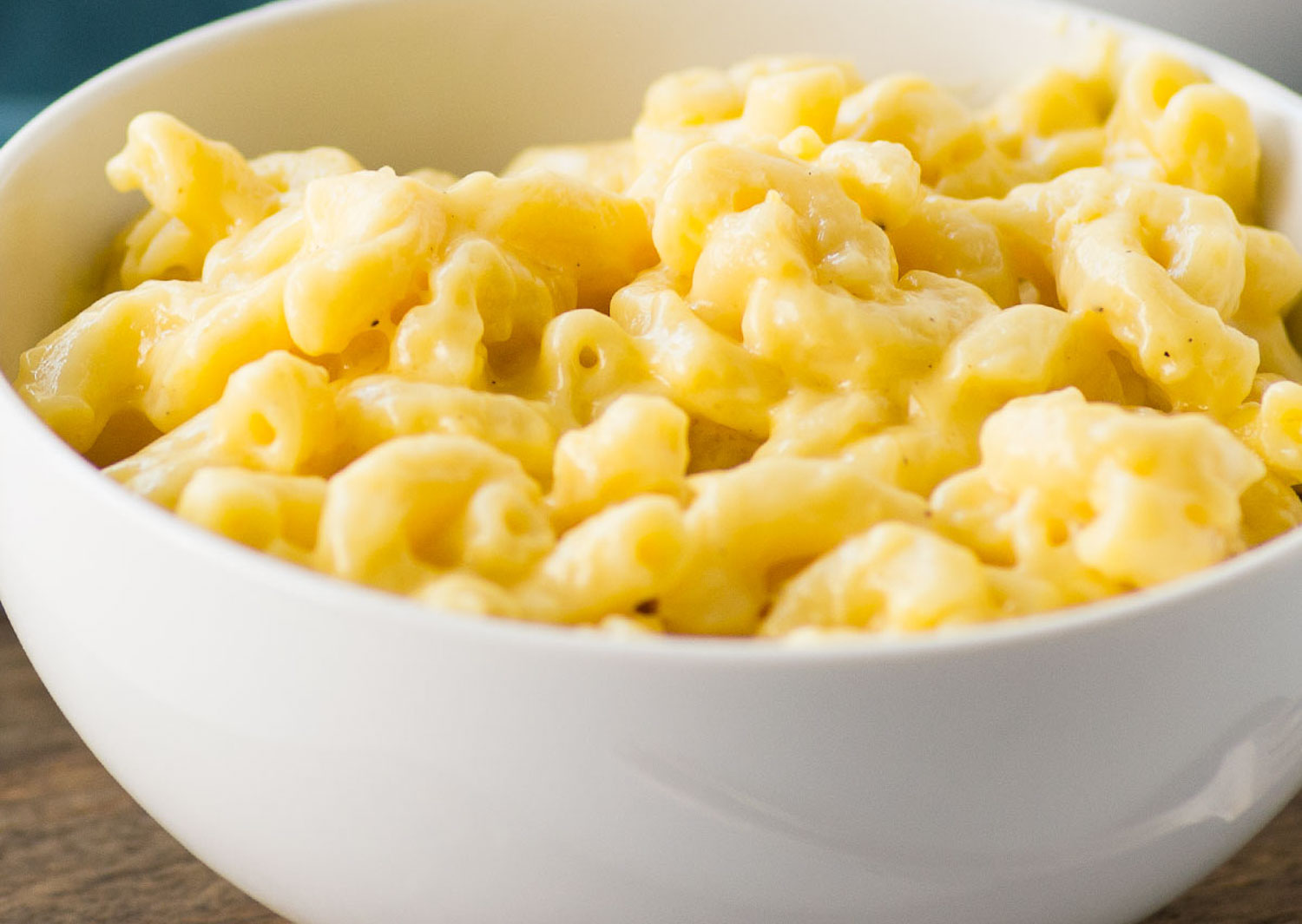 A white bowl of macaroni and cheese in it.