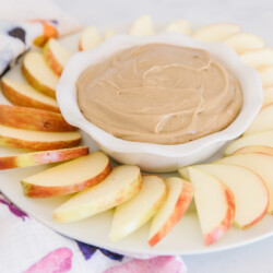 Tray of apple slices arranged around a bowl of cream cheese apple dip.
