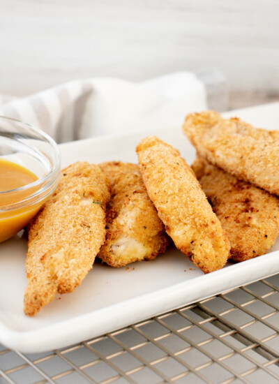 White serving dish of oven-baked chicken strips.