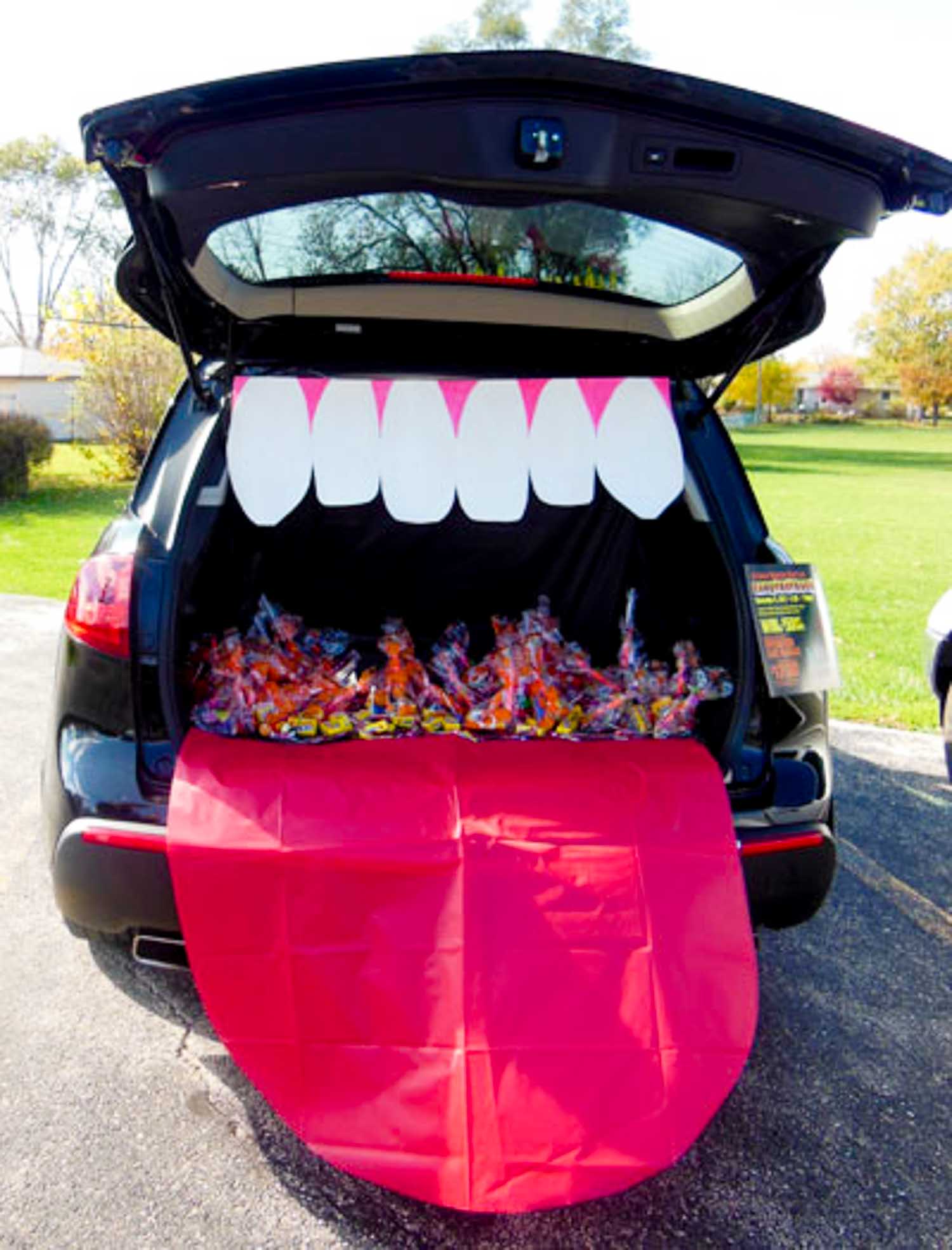 A large mouth decor in the back of a trunk with candy bags inside of it.