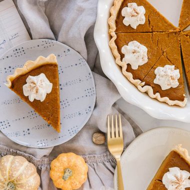 old fashioned pumpkin pie sliced with dallop of whipped cream and a full pie with slices taken out