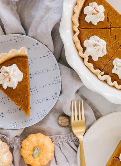 old fashioned pumpkin pie sliced with dallop of whipped cream and a full pie with slices taken out