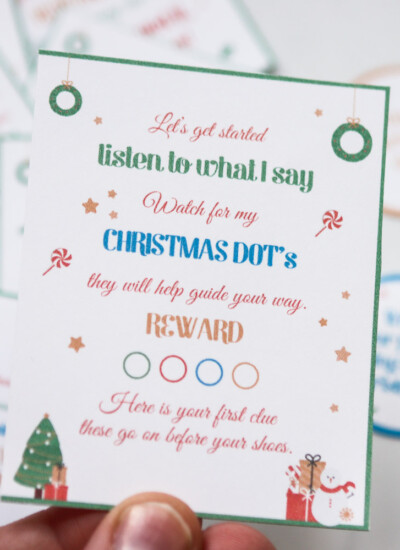 Person holding a card that reads "Let's get started listen to what I say What for my Christmas Dot's they will help guide your way Reward Here is your first clue these go on before your shoes."