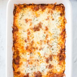 Baking dish of lasagna topped with melted cheese.