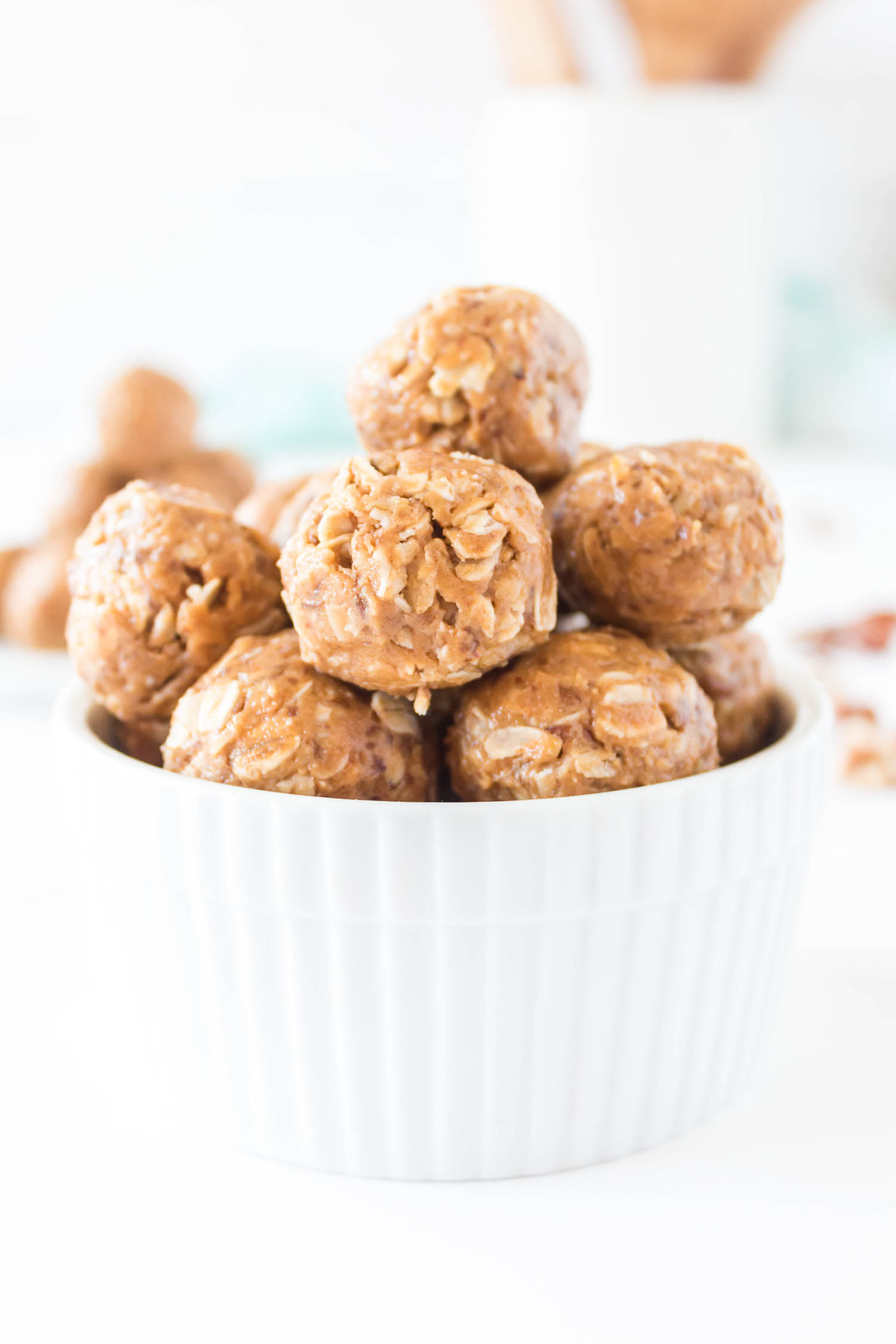 A white fluted bowl with stacks of protein balls in it on a white counter.