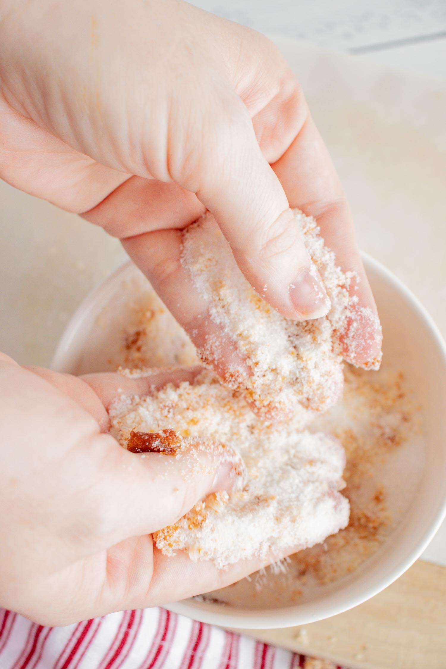 A white bowl with hands mixing white sugar and molasses