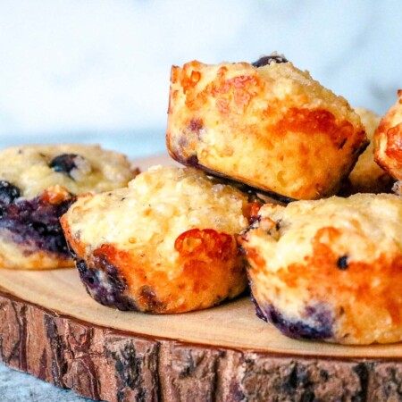 Blueberry muffins piled on a wooden board.