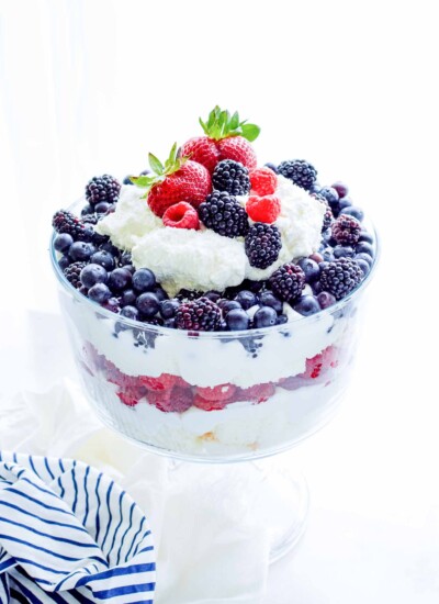 Coconut berry trifle topped with colorful berries in a glass dish.