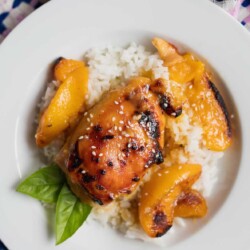 Plate of peach chicken thighs over rice.