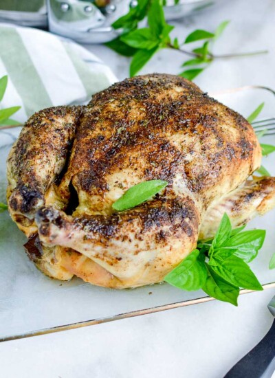 Roasted chicken on a glass tray with greens.