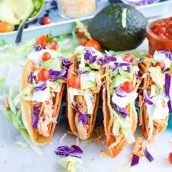 Colorful shredded chicken tacos on a marbled countertop.