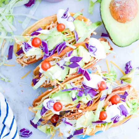 Shredded chicken tacos on counter with avocado.
