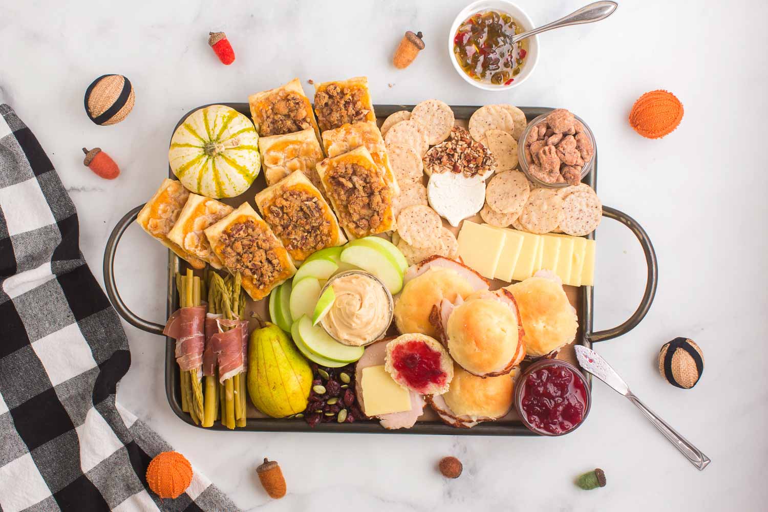 A full Thanksgiving charcuterie board with décor around the board.