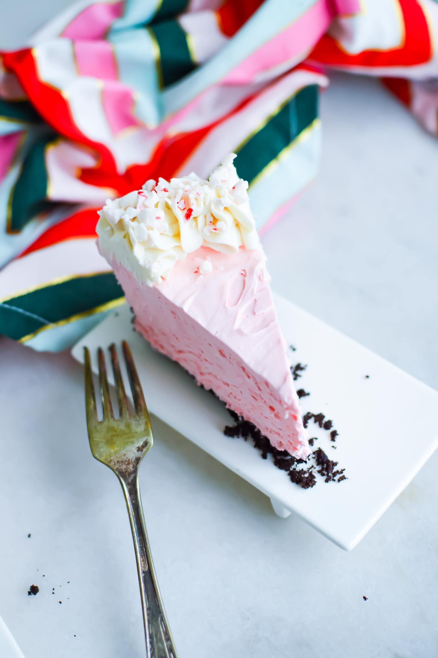 A slice of holiday dessert with a silver fork and a colorful towel.
