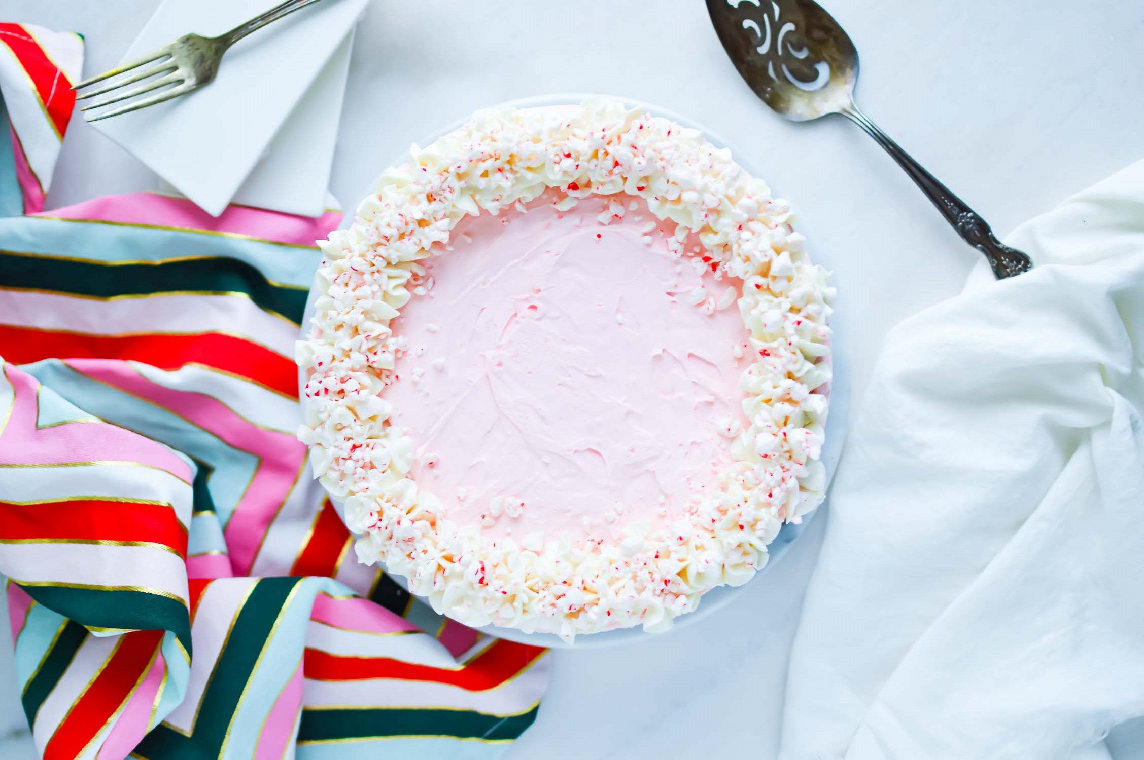 A whole peppermint pie with a colorful towel and a serving utensil.