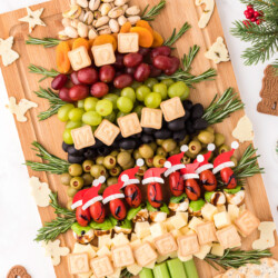 Charcuterie board in the shape of a Christmas tree made out of fruit, nuts, olives, and more.
