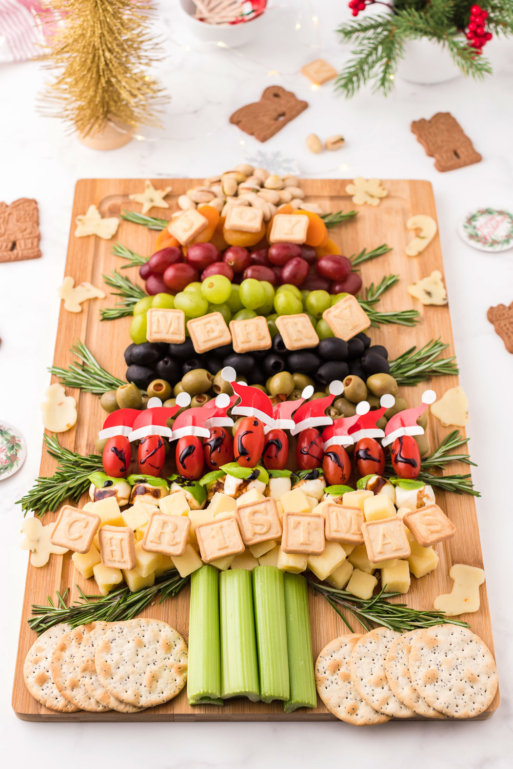 A wooden board with snacks, fruits and food in the shape of a Christmas tree.