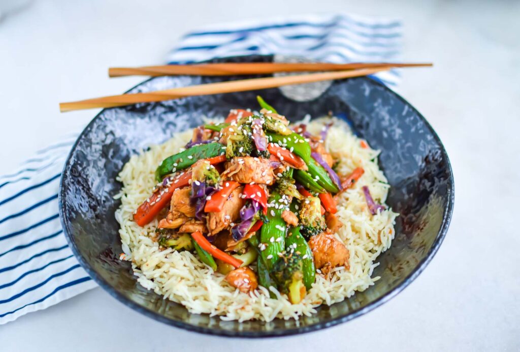 vegetables and chicken stirfry over rice in a bowl