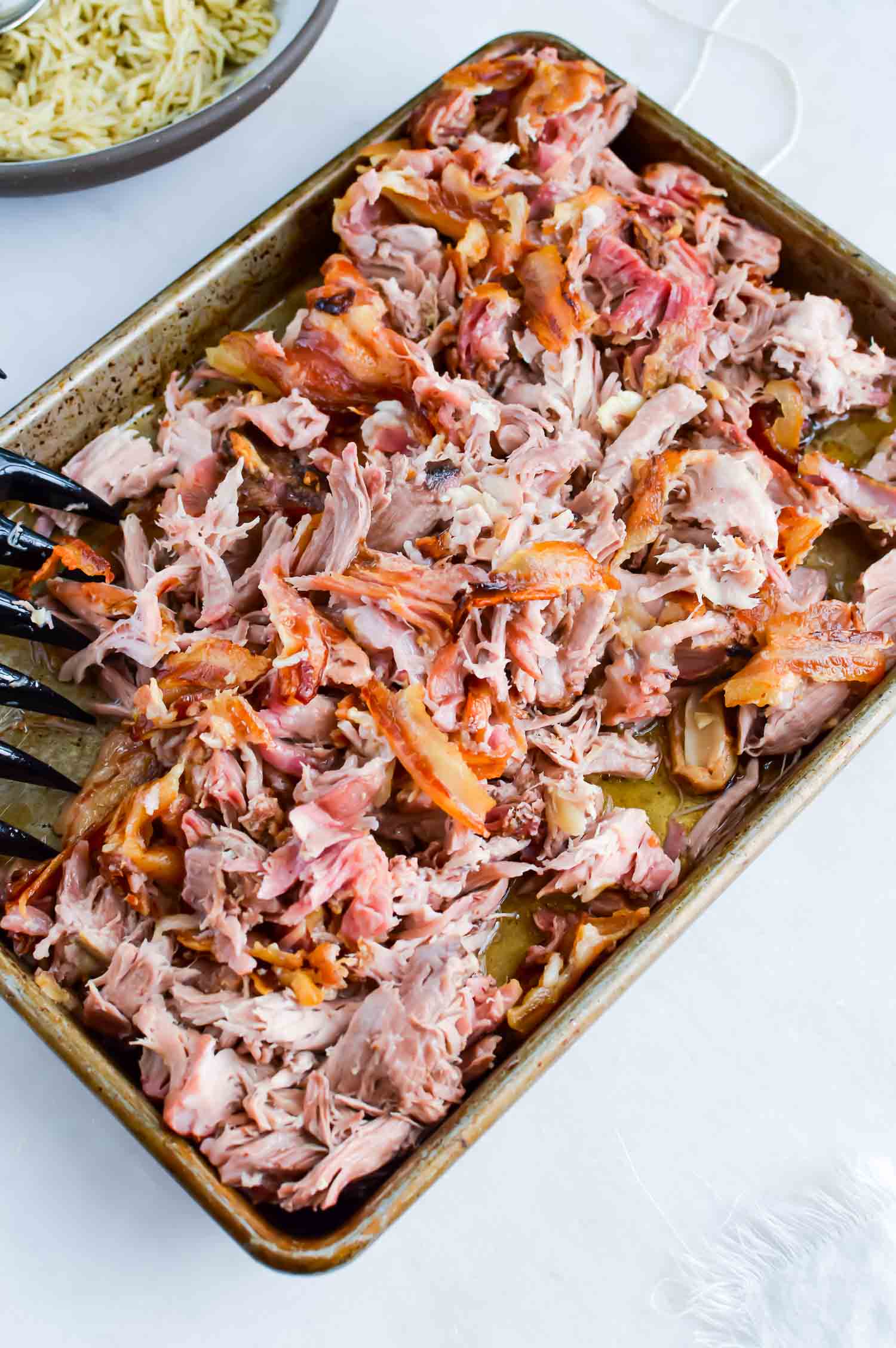 A pan of shredded pork and bacon pieces with a claw on the side.