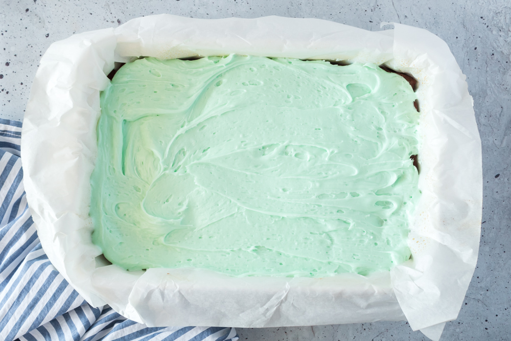 A pan of brownies with green frosting on it.