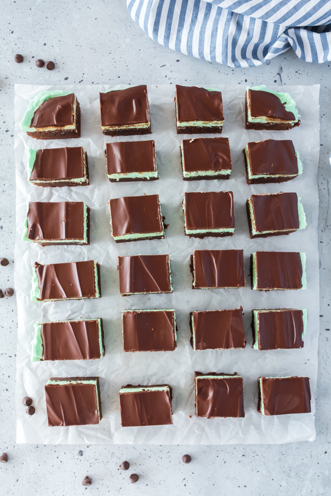 Parchment paper with cut brownies on it in rows.
