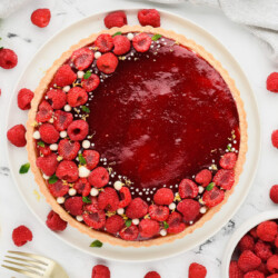 Raspberry tart decorated with fresh raspberries in the shape of a crescent.