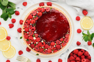 Raspberry tart decorated with fresh raspberries in the shape of a crescent.