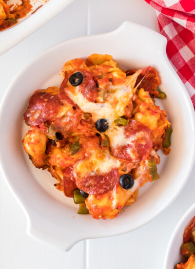 Cheesy pizza tortellini on a white plate.