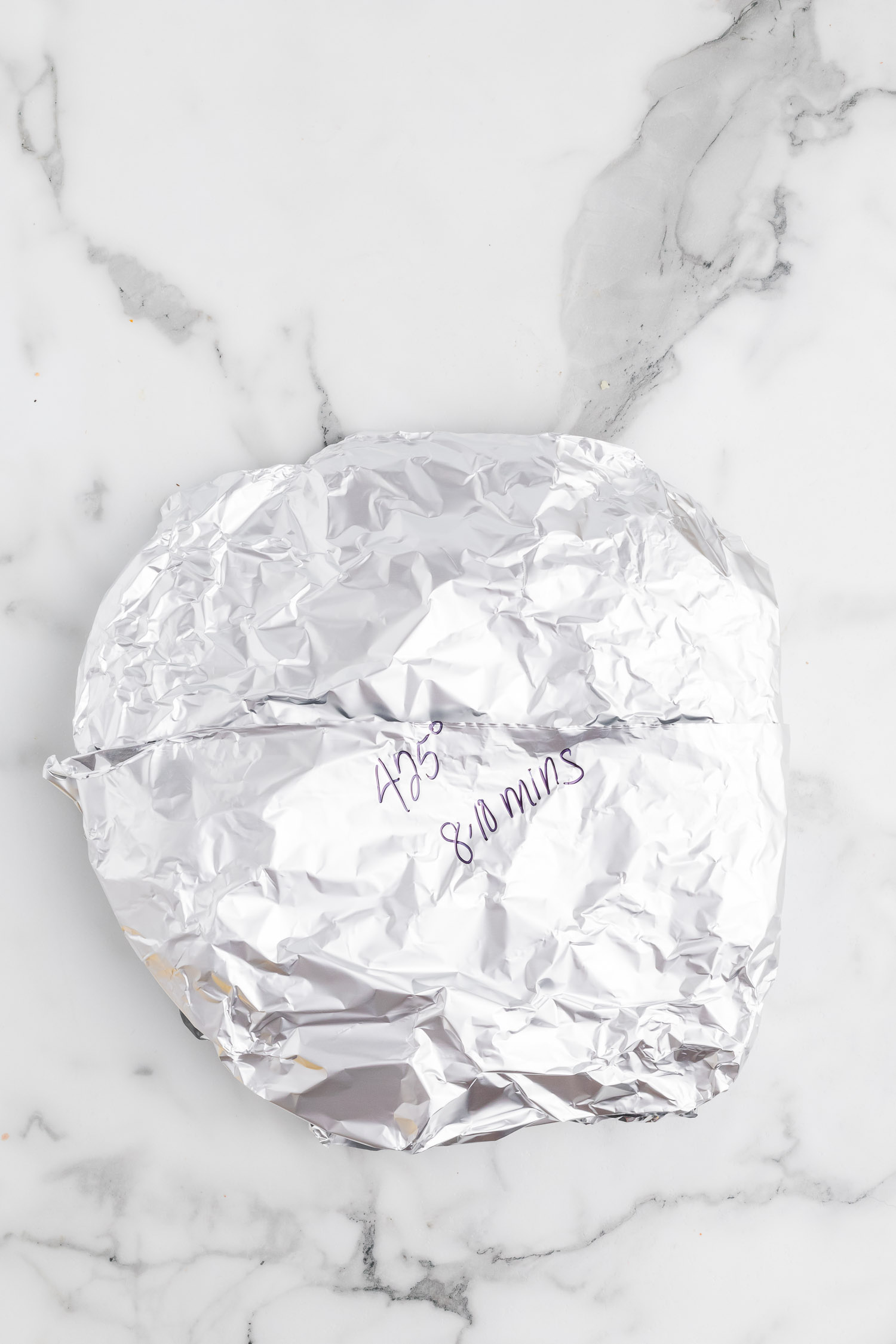 A mound of tin foil with the words "425 degrees 8-10 minutes" on it. 