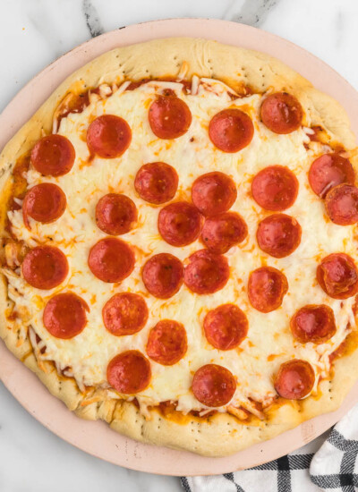 Pepperoni pizza on a wooden board.