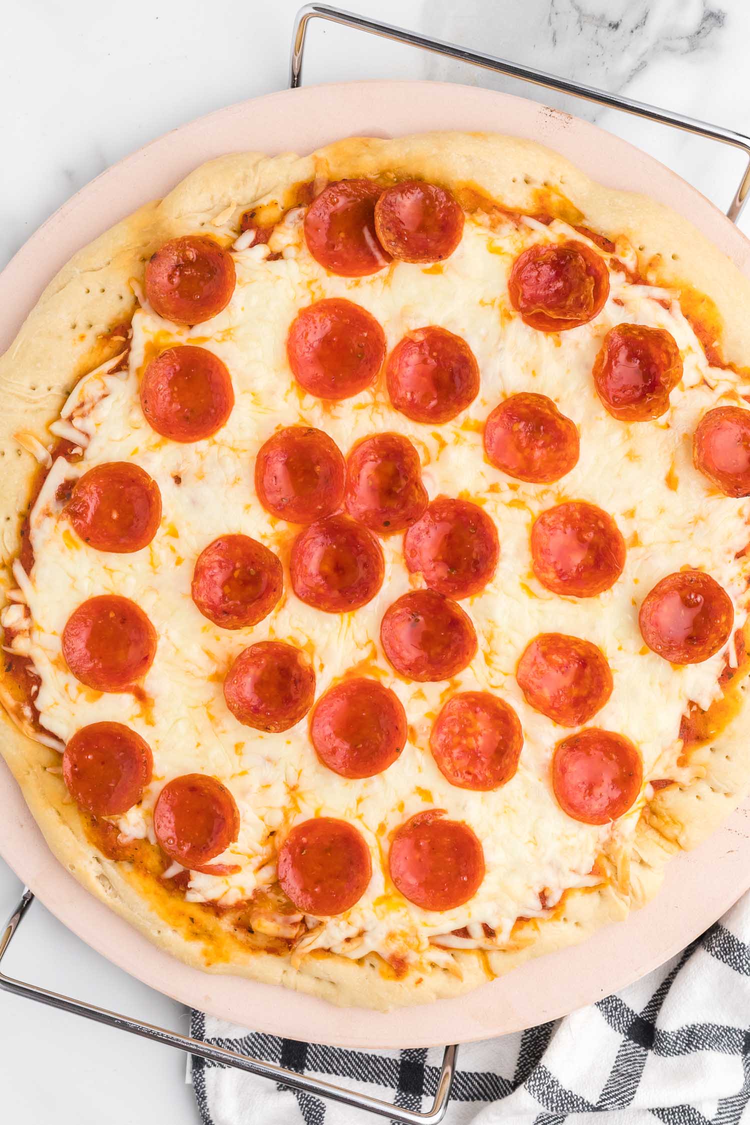 A whole pepperoni pizza on a pizza stone.