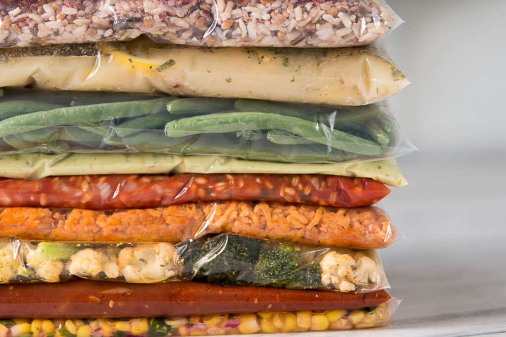 freezer meals in gallon bags stacked with food inside each.