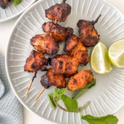 air fryer tandoori chicken on a plate with lemon and mint.